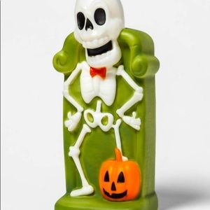 Skeleton laughing while standing over a pumpkin